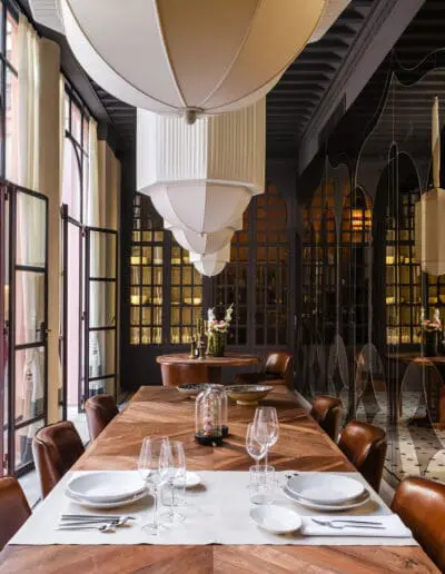 Recdi8 Living Interior Design - Marrakech Riad Restoration - Dining Room with Bespoke Wooden Tables. Aged Mirror Mosaic on the Right